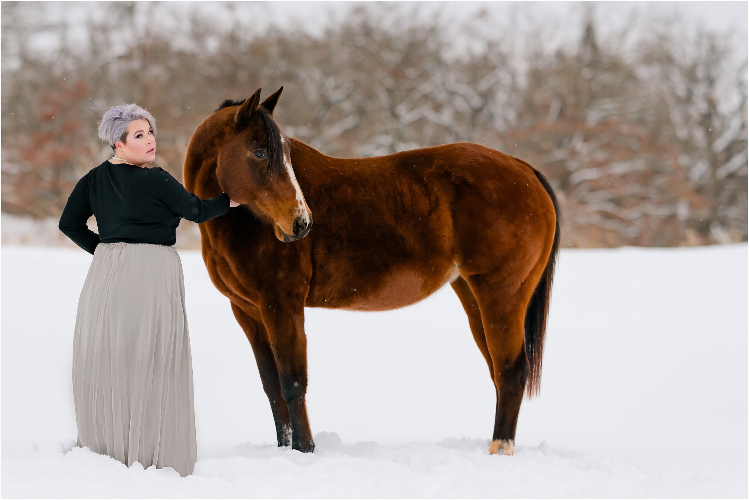  Girl with grey hair in a pixie cut with her senior quarter horse mare, standing in the snow in Arcadia Oklahoma. Grey skirt outfit for equestrian portrait session 