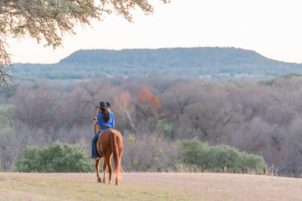 A high school rodeo queen rides her senior barrel horse toward a scenic Texas background during her high school senior portraits with an equestrian photographer. Scenic locations are possible, just ask around to friend and relatives for ideas!