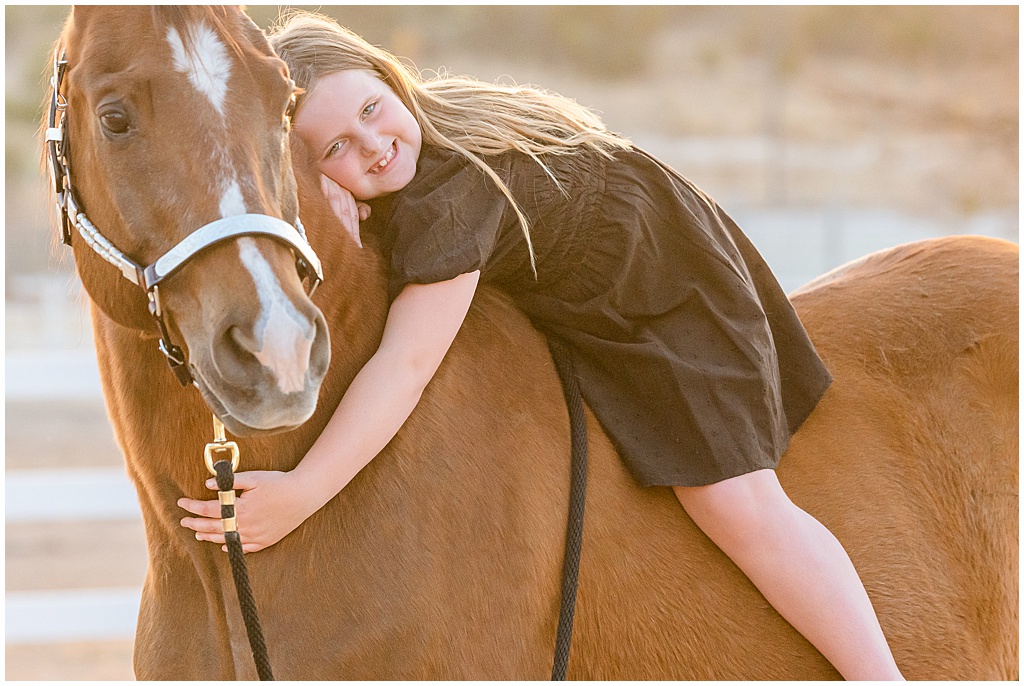 A young girl sits horseback and hugs the neck of her chestnut gelding